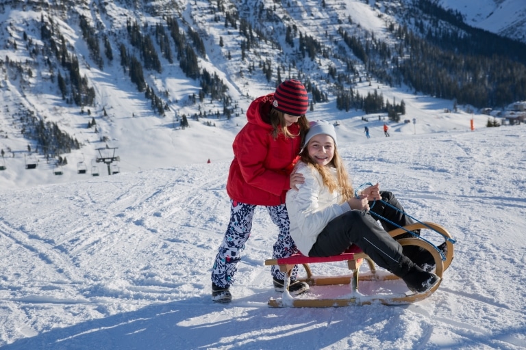 Symbolbild Rodeln in Landeck und Umgebung: zwei Mädchen im Winterurlaub beim Rodeln im Tiroler Oberland