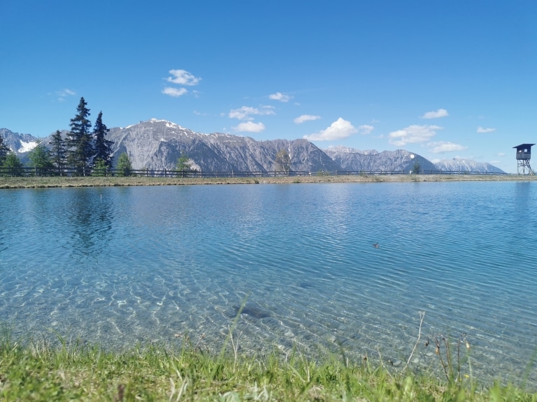 Ein blauer Speicherteich lädt im Tiroler Oberland zum Füßen hineinstrecken ein