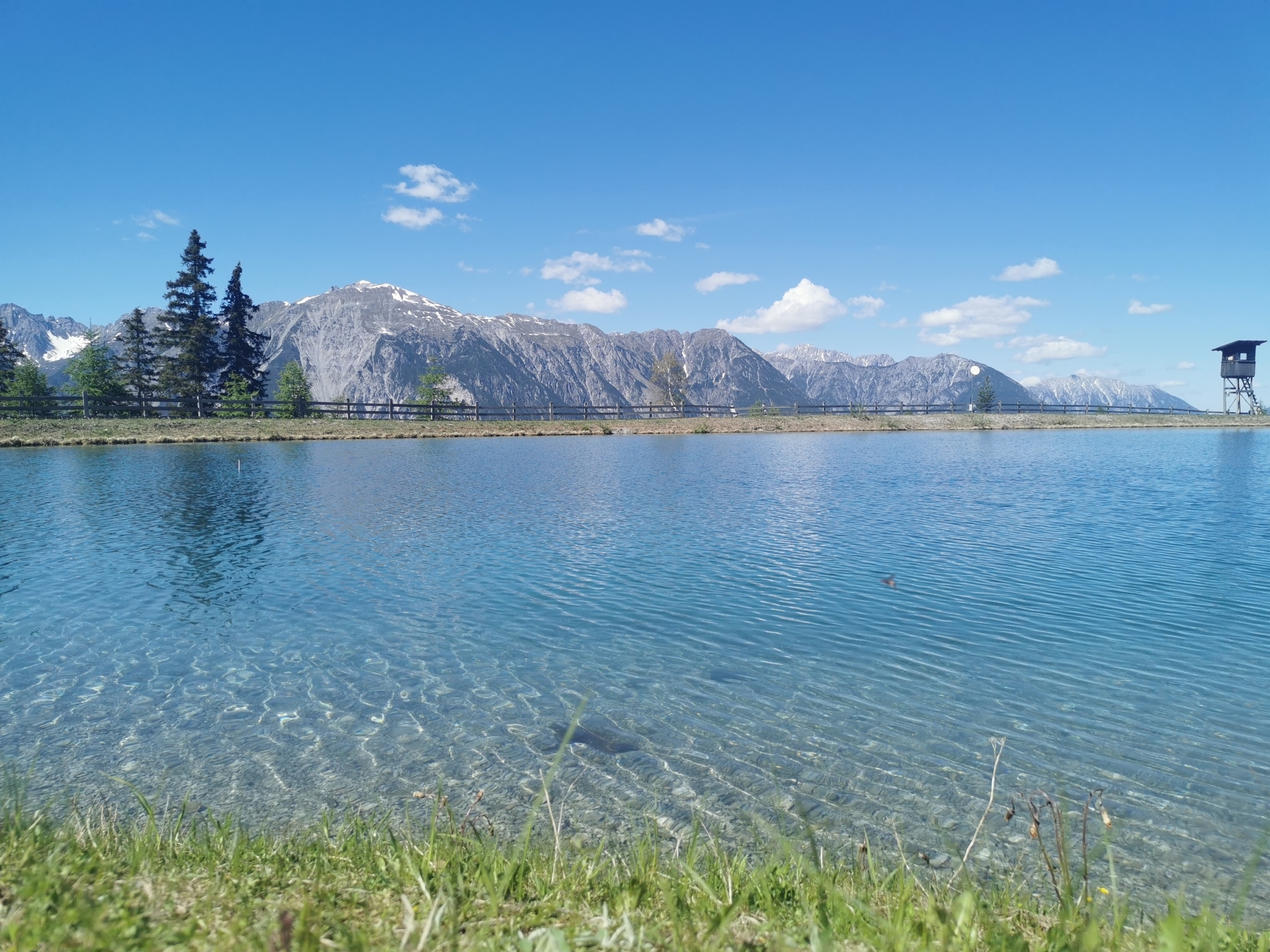 Ein blauer Speicherteich lädt im Tiroler Oberland zum Füßen hineinstrecken ein